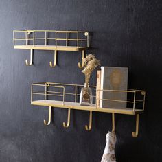 two shelves with books and vases on them in front of a black wall,