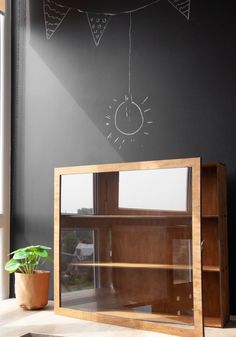 a wooden cabinet sitting in front of a chalkboard wall with a clock drawn on it