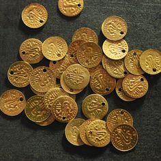 lots of gold coins sitting on top of a black cloth covered floor with holes in the middle