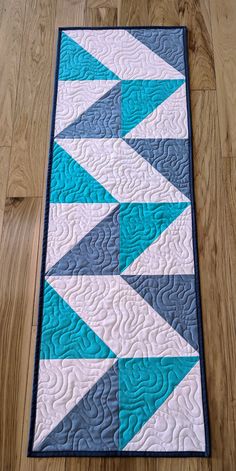 a blue and white quilted table runner sitting on top of a hard wood floor