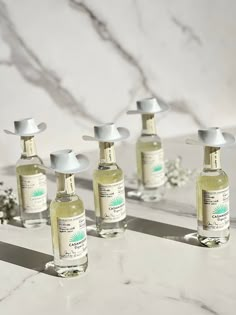 six bottles of hand sanitizers sitting on a marble counter with flowers in the background