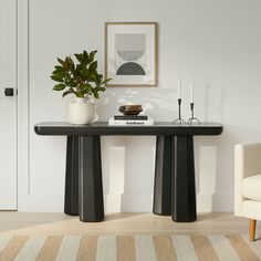 a black table with two white vases on it and a plant next to it