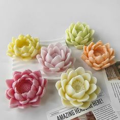 four different colored flowers sitting on top of a magazine