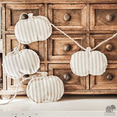 three pieces of fabric hanging from strings on a dresser