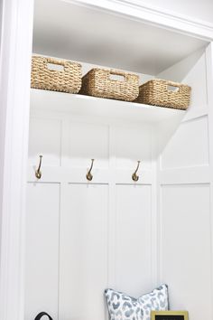 a bench with two baskets on top of it next to a wall mounted coat rack