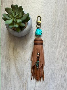 a leather keychain with a turquoise bead hanging from it's side