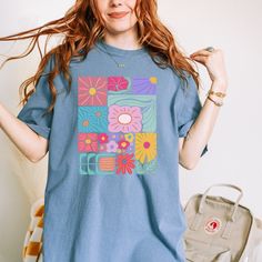 Add a touch of boho to your wardrobe with our Boho Flower T-Shirt. Featuring a beautiful floral design, this shirt will add a unique and playful touch to your style. Embrace your inner flower child and stand out from the crowd with this abstract yet stylish t-shirt. Retro Short Sleeve T-shirt With Floral Print, Bohemian Spring T-shirt With Graphic Print, Hippie Multicolor T-shirt For Spring, Artsy Printed Summer Tops, Artsy Printed Tops For Summer, Blue Cotton Tops With Floral Patchwork, Bohemian Printed T-shirt For Spring, Bohemian Blue Printed T-shirt, Spring Hippie T-shirt With Screen Print