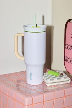 a coffee cup sitting on top of a pink table