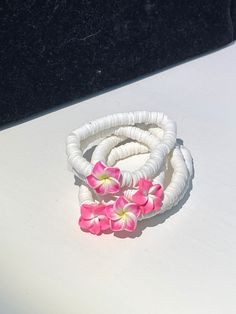 This is a white beaded bracelet with a Hawaiian flower in the center. There are 7 colors of the flower. the colors include pink and yellow, pink and white, magenta and yellow, dark purple and yellow, green and yellow, blue and yellow, white and yellow. Each bracelet is about 6-7 inches in circumference and the bracelets are stretchy. White Flower Jewelry For Vacation, Pink Flower-shaped Jewelry For Vacation, Pink Flower Jewelry For Vacation, Adjustable White Jewelry With Flower Decoration, Yellow Flower Bracelet For The Beach, Yellow Flower Bracelets For Beach, Yellow Flower Bracelets For The Beach, Handmade White Flower Bracelet, Flower Shaped Bracelets For Beach