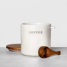 a white coffee mug with a wooden spoon on the side next to it, sitting on a table