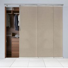 an open sliding door in a closet with clothes hanging on the hangers and drawers