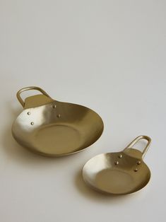 two brass serving dishes on a white surface