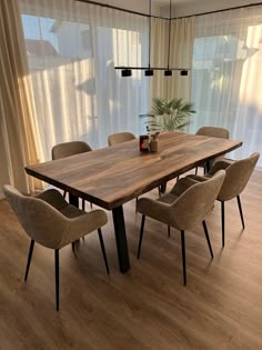 a dining room table with six chairs and a potted plant