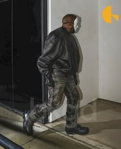 a man in black jacket and jeans walking down the street