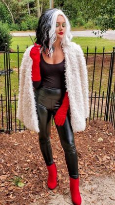 a woman in black leather pants and red gloves posing for the camera with her hands on her hips