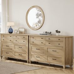 a large wooden dresser sitting in a living room next to a window with a round mirror on it