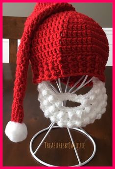 a crocheted red and white hat sitting on top of a wooden table next to a wire rack