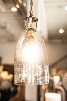 a glass light hanging from a ceiling in a room with lights on the ceiling and tables