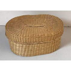 a round wicker box sitting on top of a white floor next to a wall