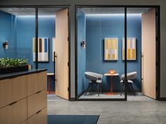 an office with blue walls and two chairs in front of a table that has plants on it