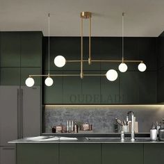 a kitchen with green cabinets and lights hanging from the ceiling over the counter top,