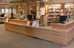 an empty library with two people working at the desks and several bookshelves