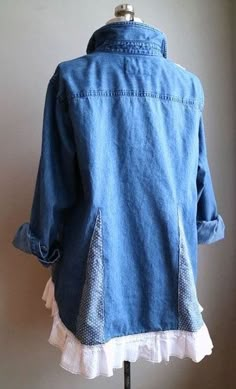 a woman's jean jacket with ruffles on the bottom and back, sitting on a mannequin