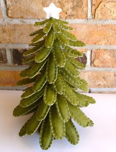 a small green christmas tree sitting on top of a white table next to a brick wall