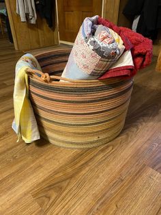 a large basket filled with clothes on top of a wooden floor