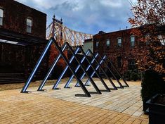 a group of metal poles sitting on top of a brick floor next to tall buildings