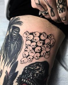 a person with tattoos on their legs and skulls in front of them, holding a cell phone