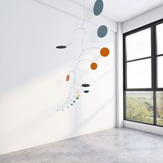 an empty room with a large window and some hanging circles on the wall next to it