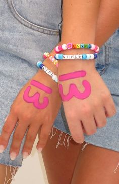 two girls with bracelets on their hands and one has the word love painted on it