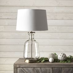 a table lamp sitting on top of a wooden cabinet next to a white ball and pine cone