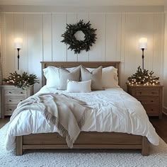 a bedroom with white bedding and christmas decorations on the wall above it is decorated with wreaths