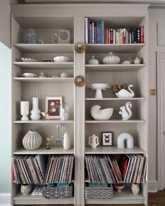 a white bookcase filled with lots of books and vinyl record's on top of it