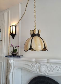 a lamp hanging from the side of a white fireplace