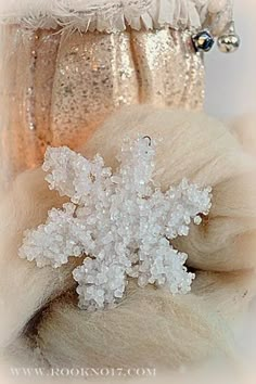 a white snowflake is sitting on top of a pile of wool and sequins