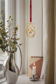 a vase filled with flowers sitting next to a window sill near a lit candle