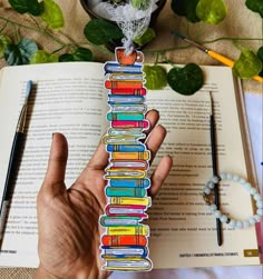 a hand holding a bookmark made out of books on top of an open book