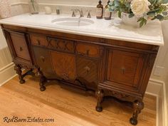 a bathroom vanity with marble top and wooden drawers, flowers in vase on the sink