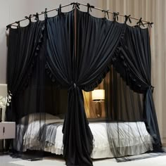 a black canopy bed with sheer curtains on it