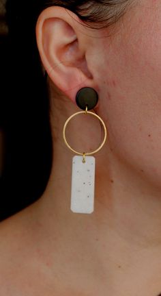 a close up of a person wearing earrings with a black and white stone