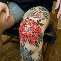 a woman sitting in a chair with a flower tattoo on her leg