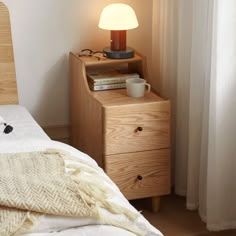 a bedroom scene with focus on the bed and bedside table, which has a lamp