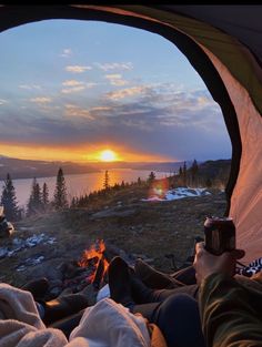 a person sitting in a tent looking out at the sunset