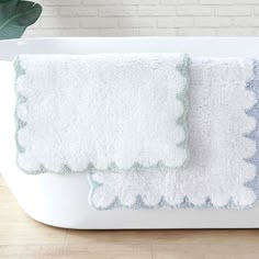 two bath mats sitting next to each other on top of a wooden floor in front of a brick wall