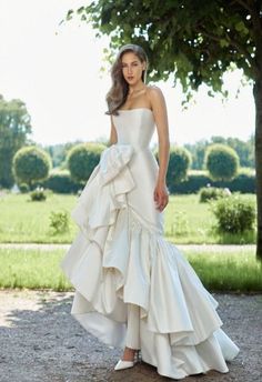 a woman in a white wedding dress standing next to a tree