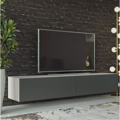 an entertainment center in front of a brick wall with a large television on it's stand