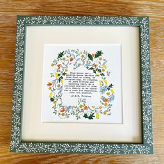 a cross stitch pattern in a frame on a wooden table